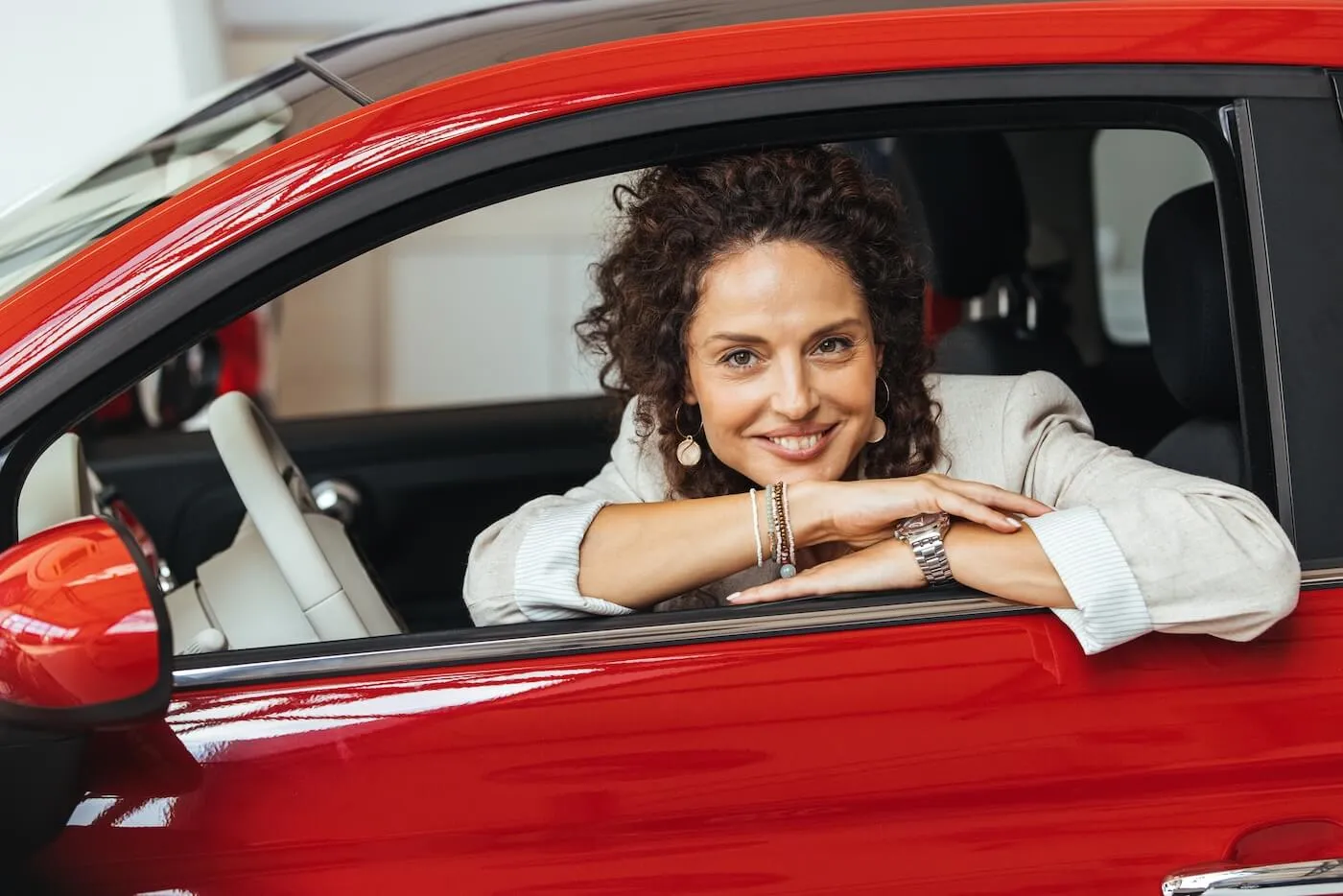 Smiling woman posing for photo while sitting in a red car