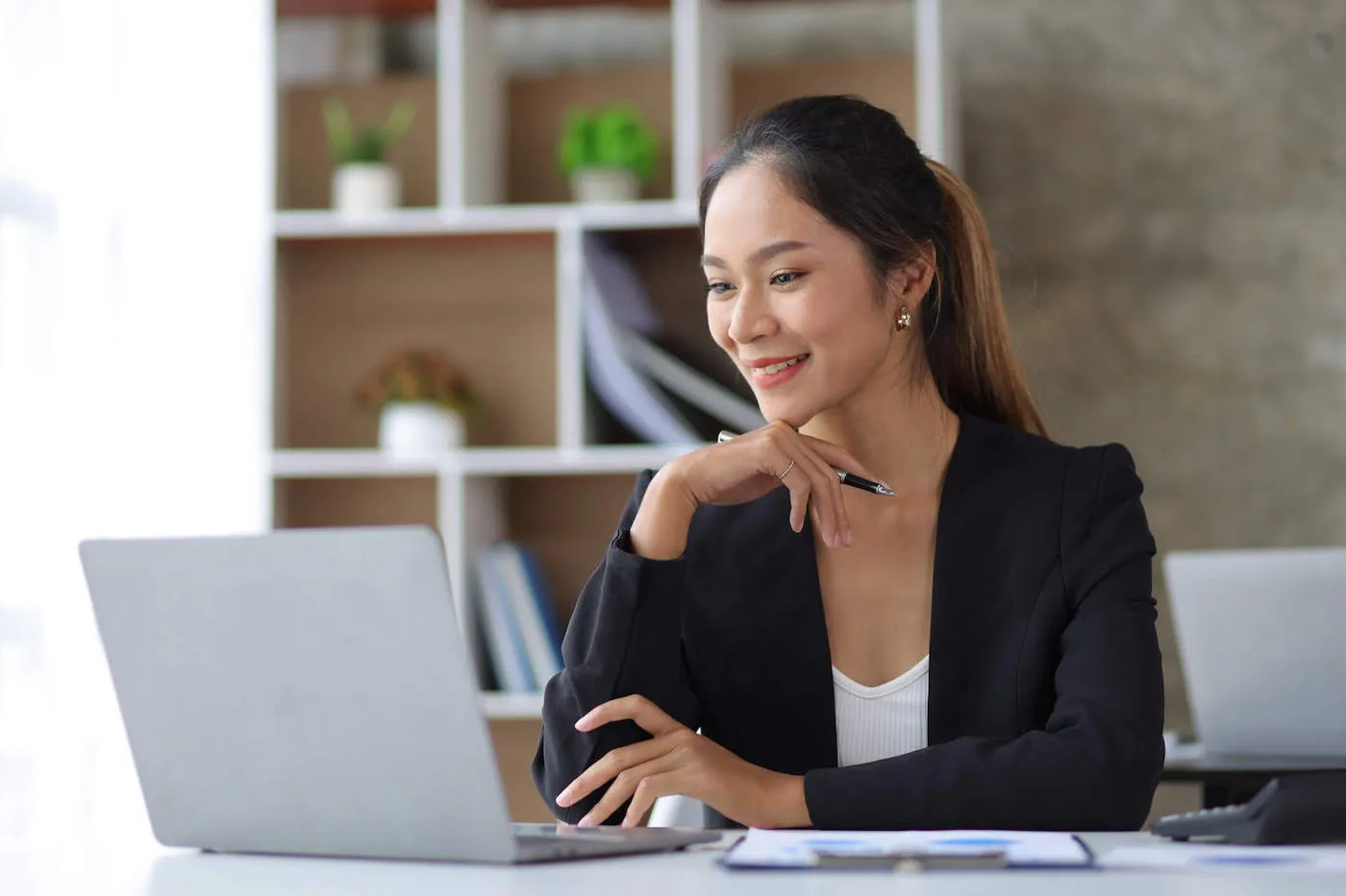 Asian business woman working on laptop on desk in office.