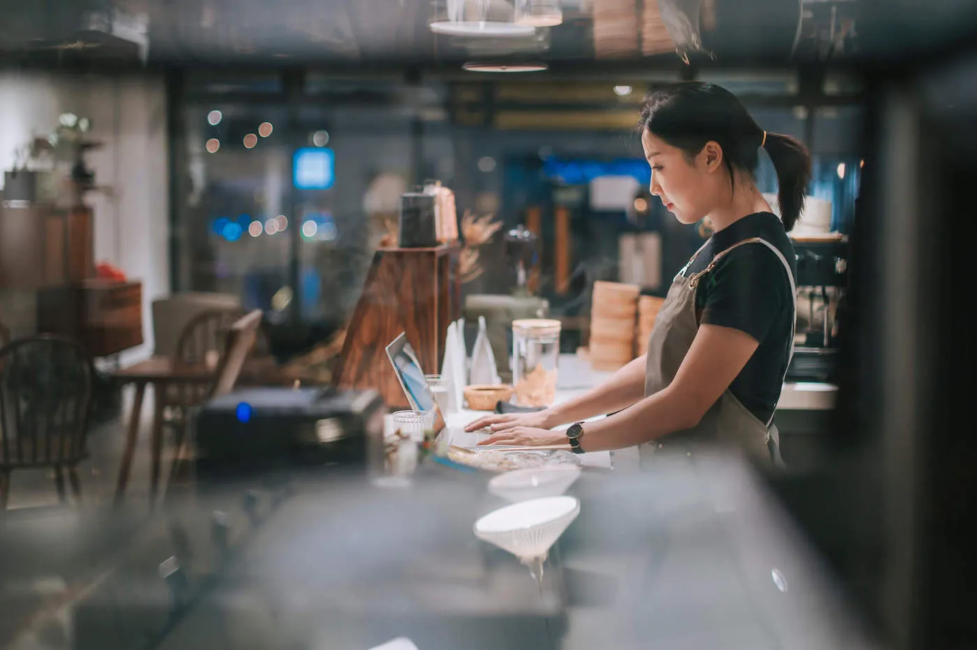 Asian Chinese female barista using laptop.