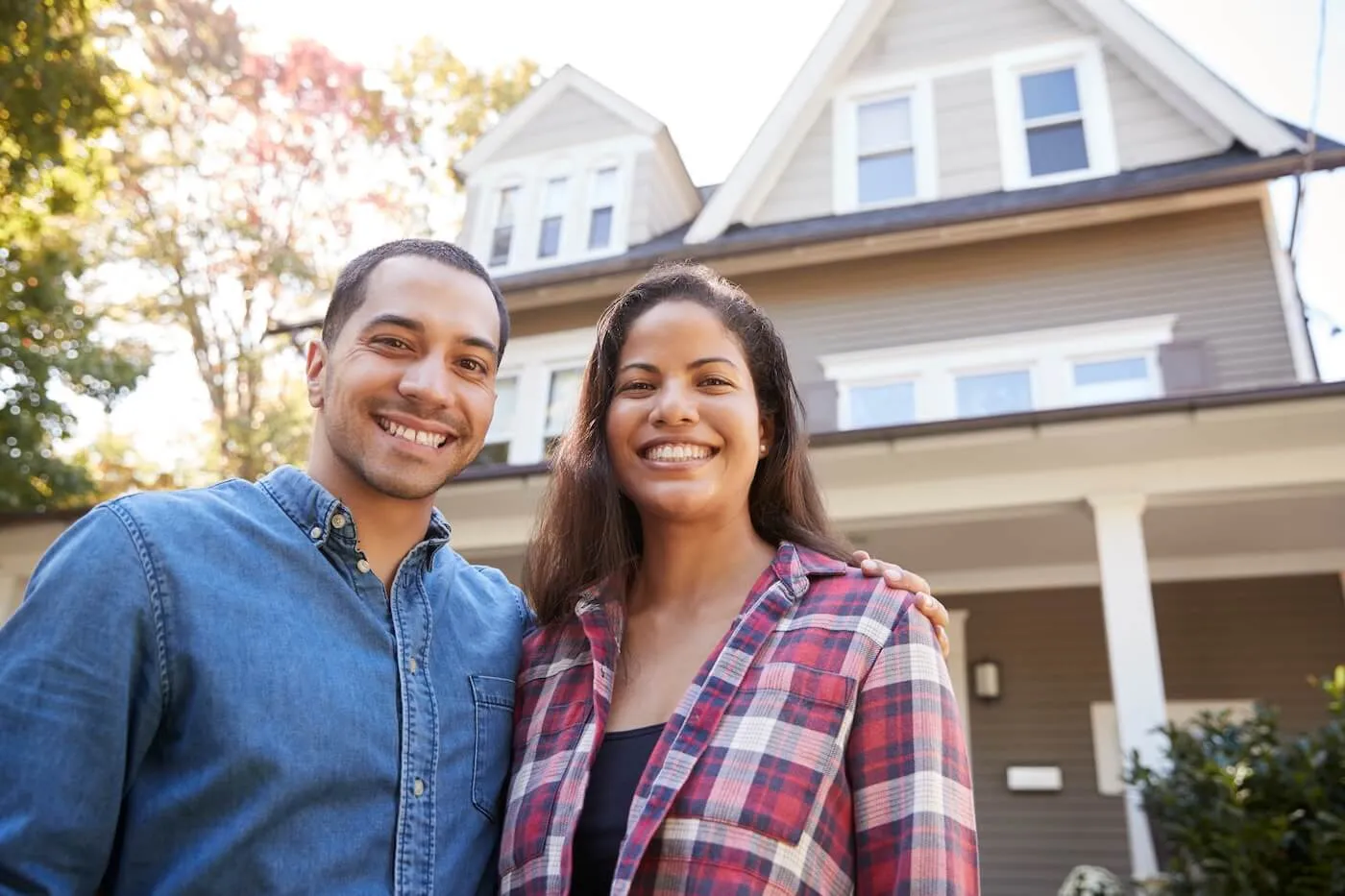 Smiling young couple standing in front of the house