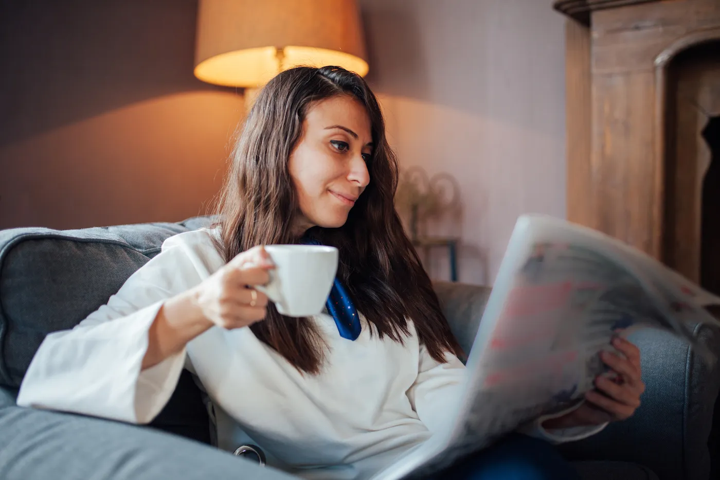 Joyful girl reading newspaper while having morning coffee in a cafe