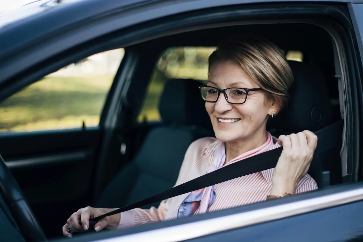 Smiling senior woman fastening her seatbelt