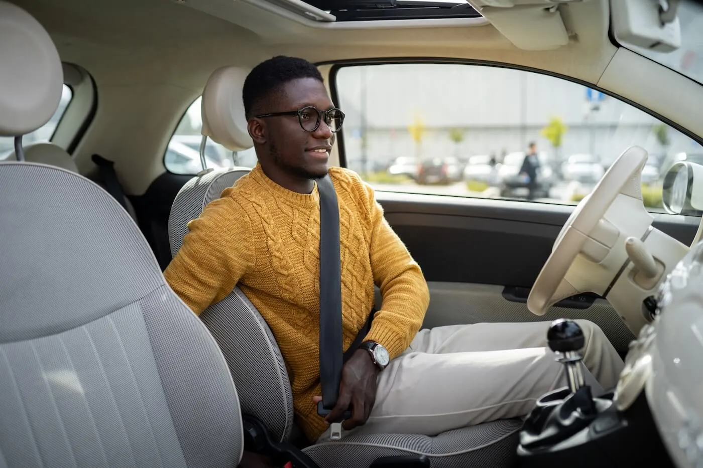 Smiling young man fastening a seatbelt in the car