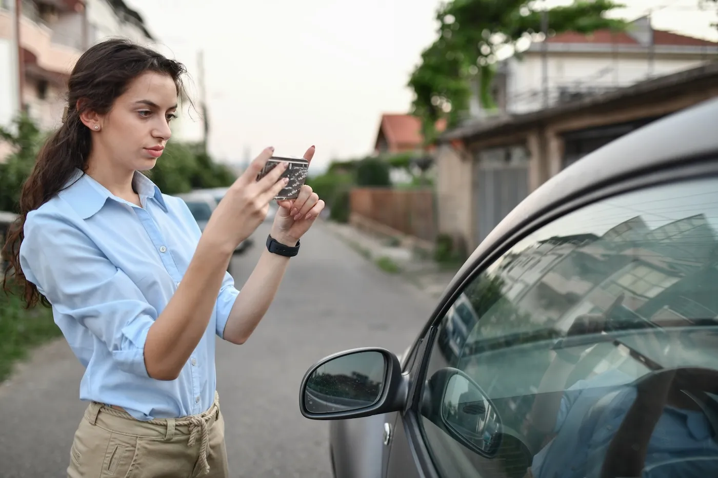 A Woman With Damaged Windshield Taking Insurance Photographs Of It.