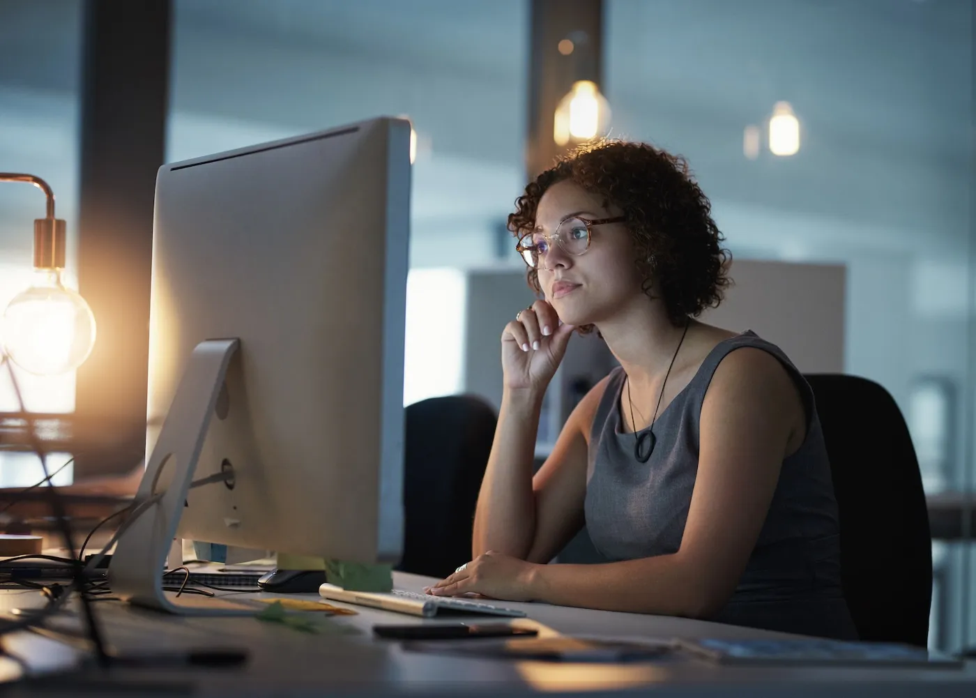 A young woman working in a modern office at night.