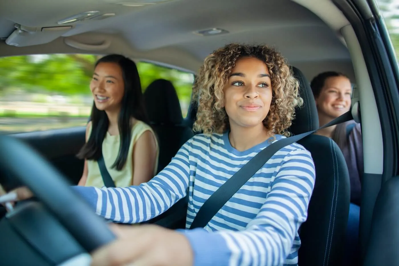 Young woman driving a car with young female passengers