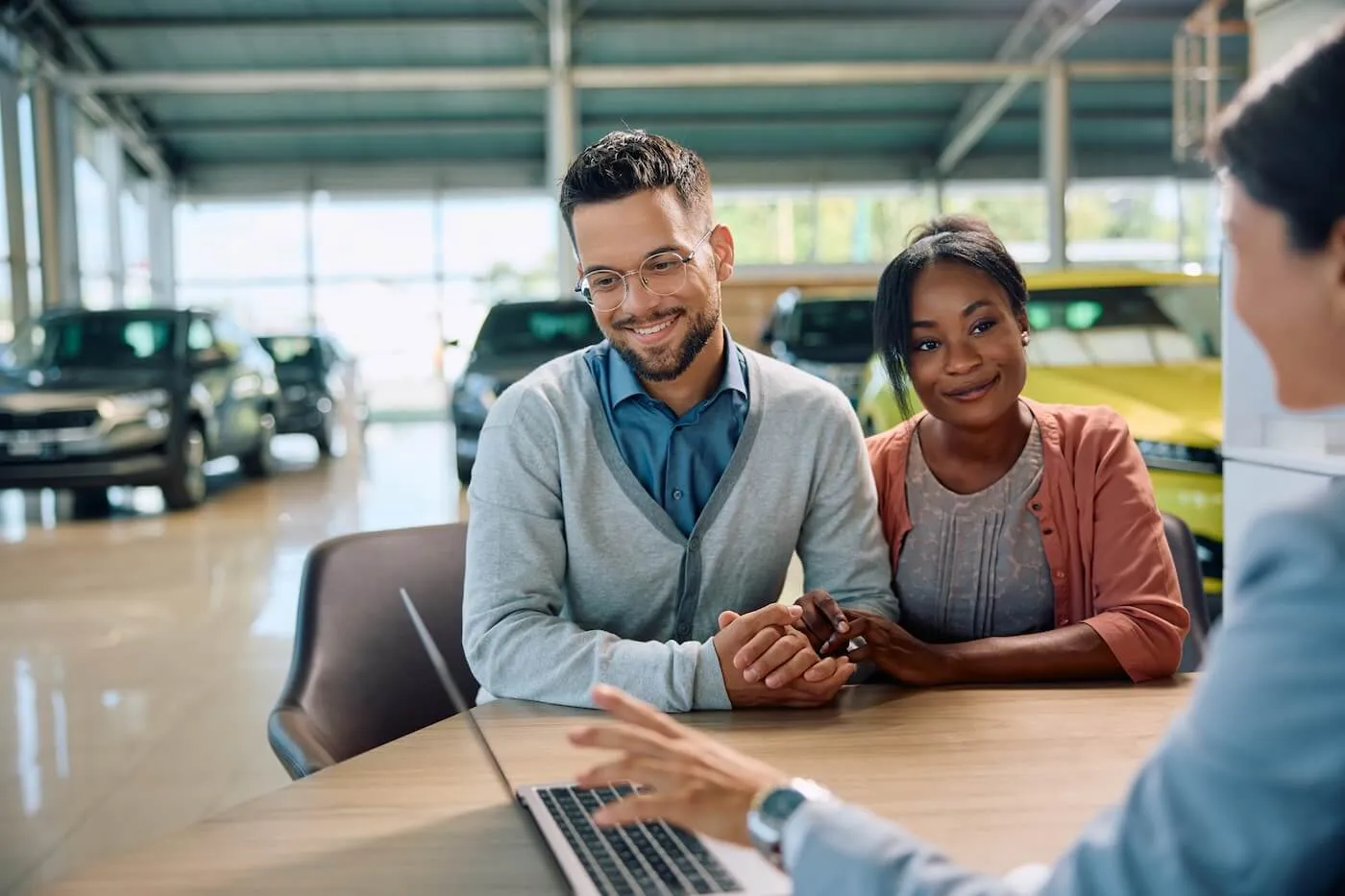 Dealership agent explains the car financing terms to a young couple