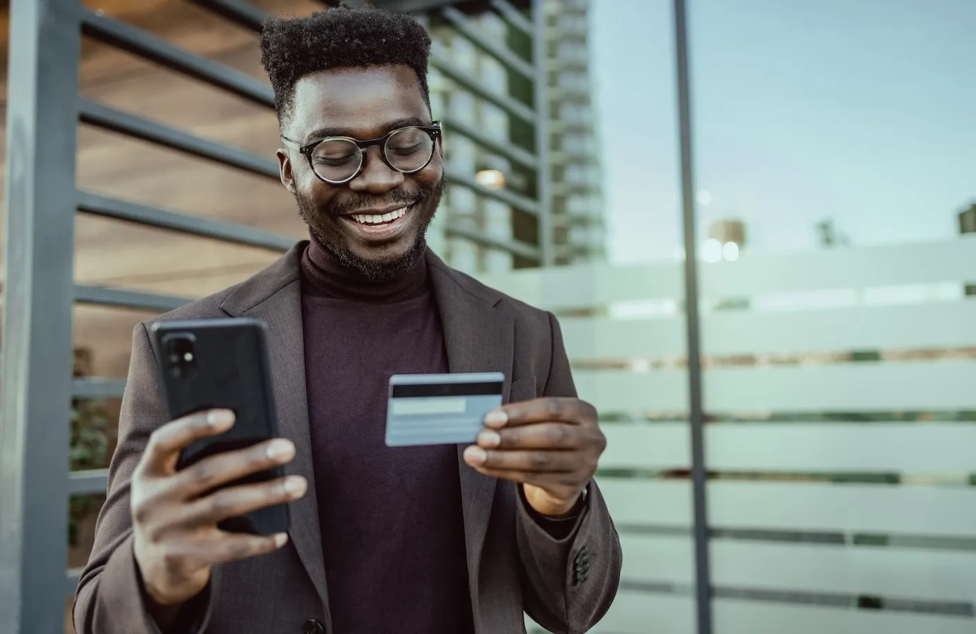 Young African-American businessman outdoors using mobile phone and credit card