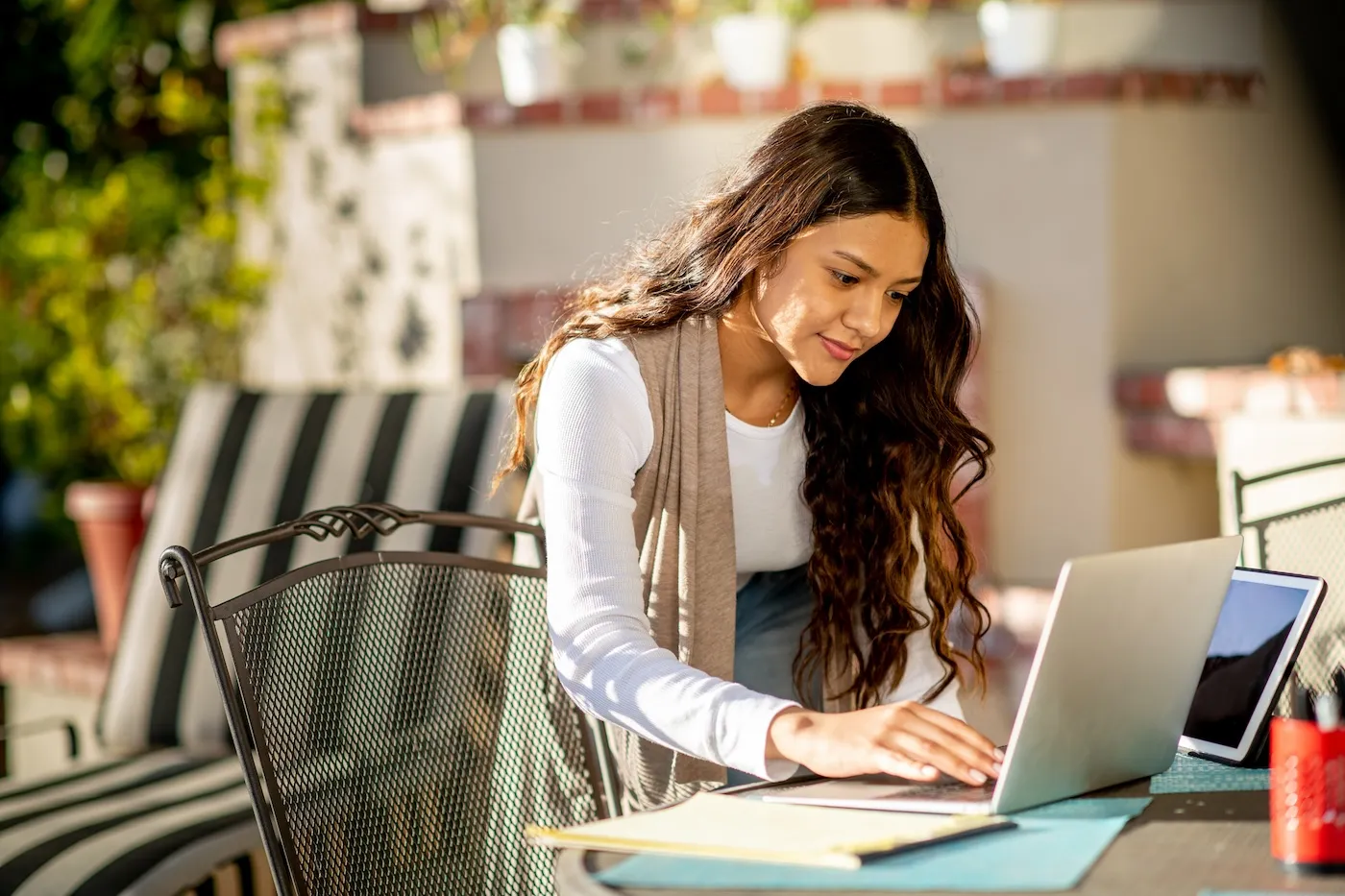 Young woman works at her make-shift office space at home in the backyard.