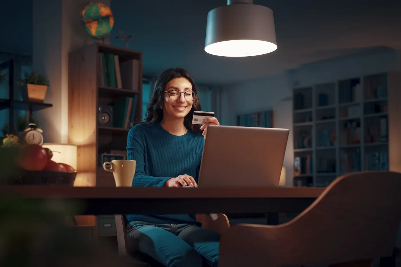 Happy woman holding a credit card and doing online shopping with her laptop