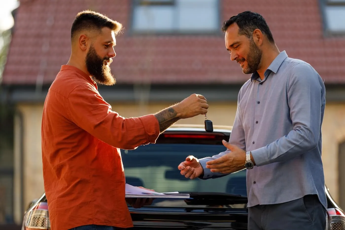 Man giving the car keys to a male buyer after selling his car