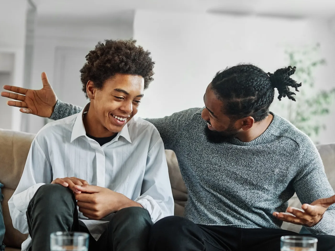 Portrait of a happy teenage boy son talking to his father at home.