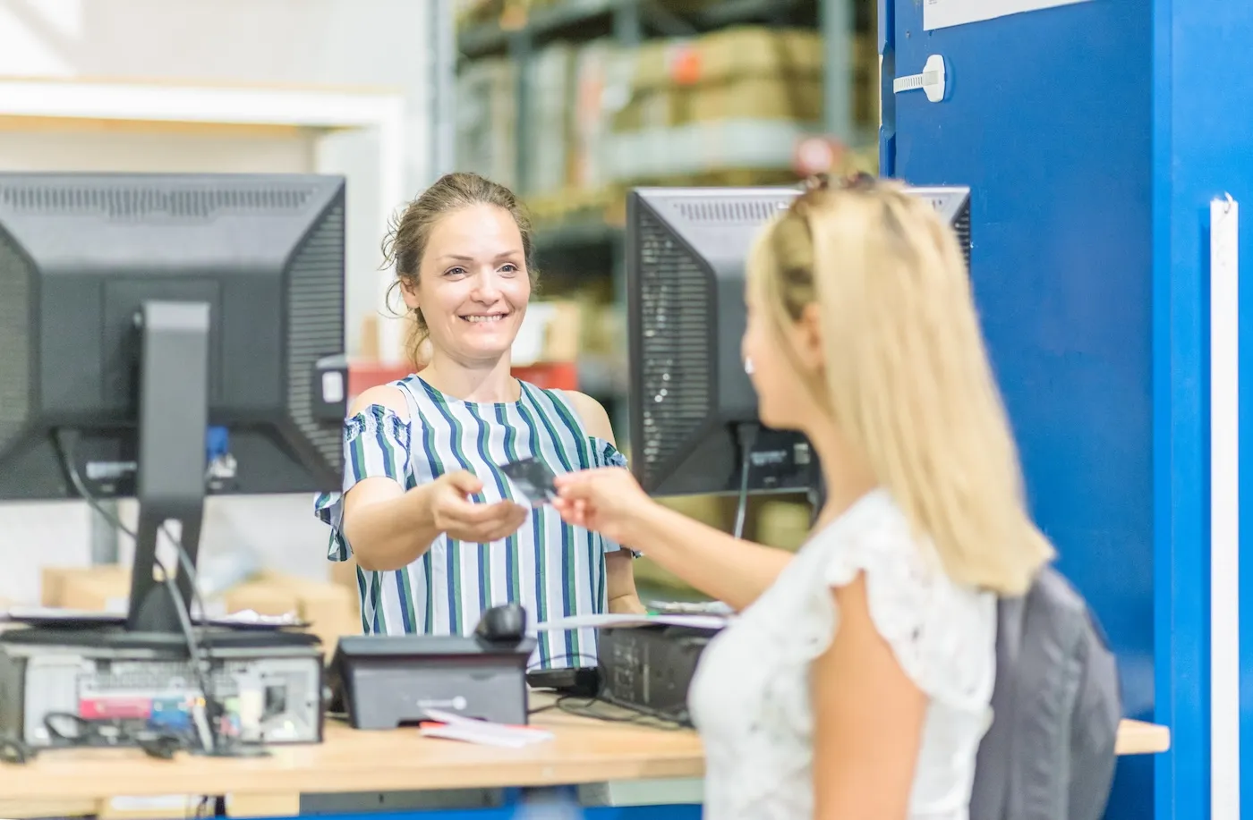 A woman handing her credit card to a cashier.