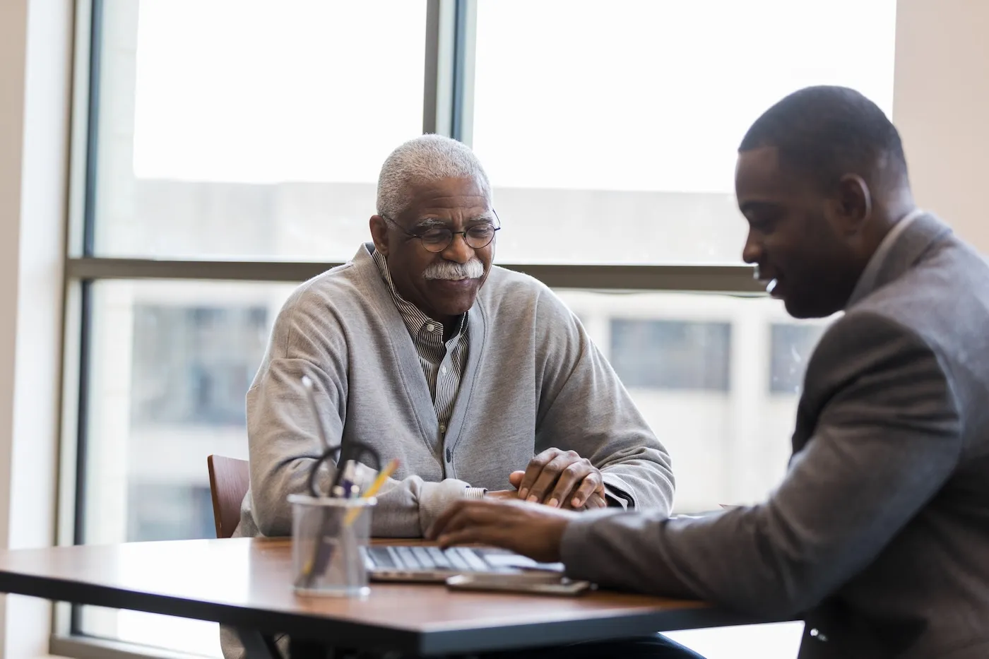 A man getting help from a banking professional about his checking accounts.