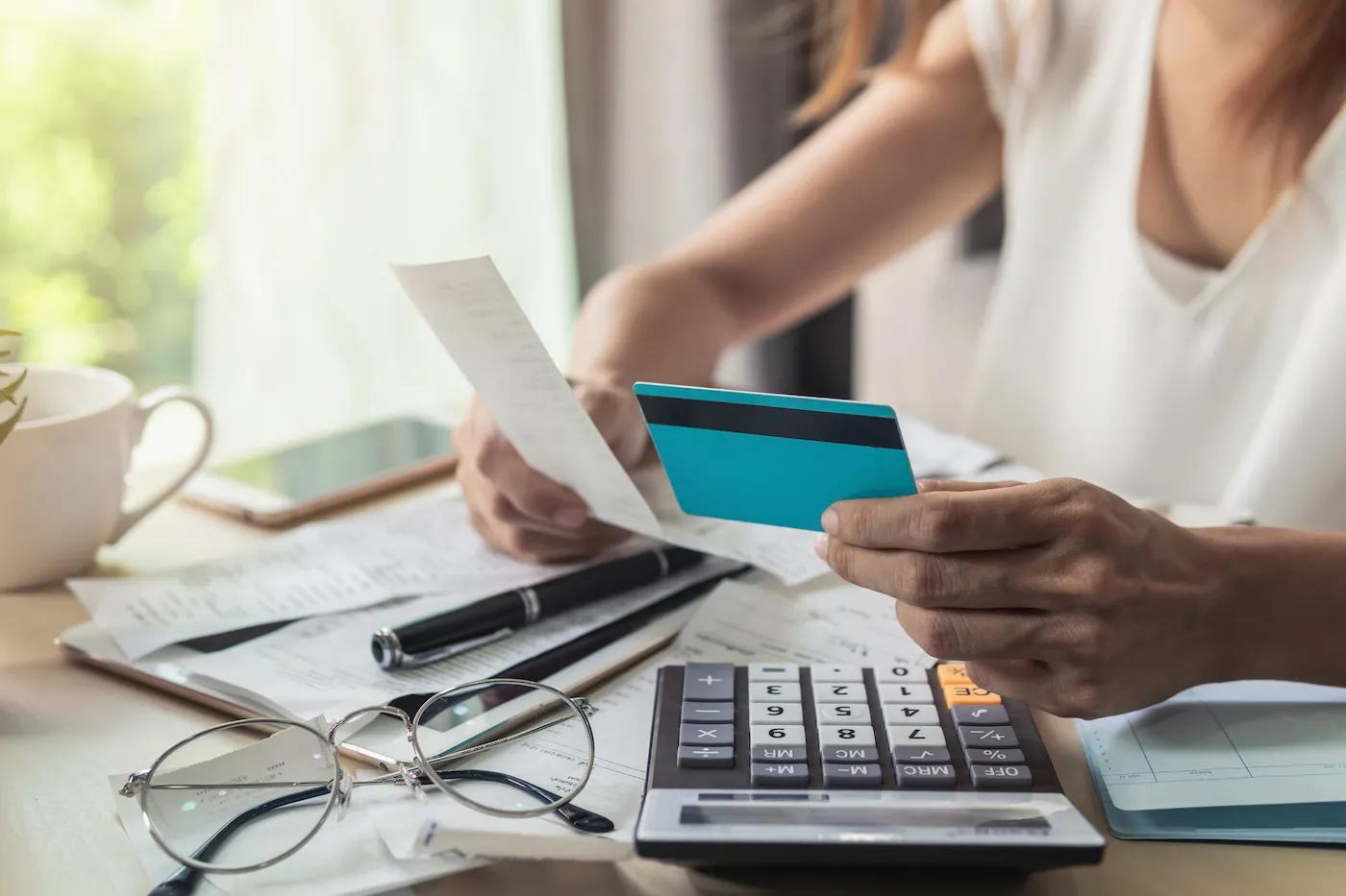 A woman holding a credit card in one hand and a receipt in the other.