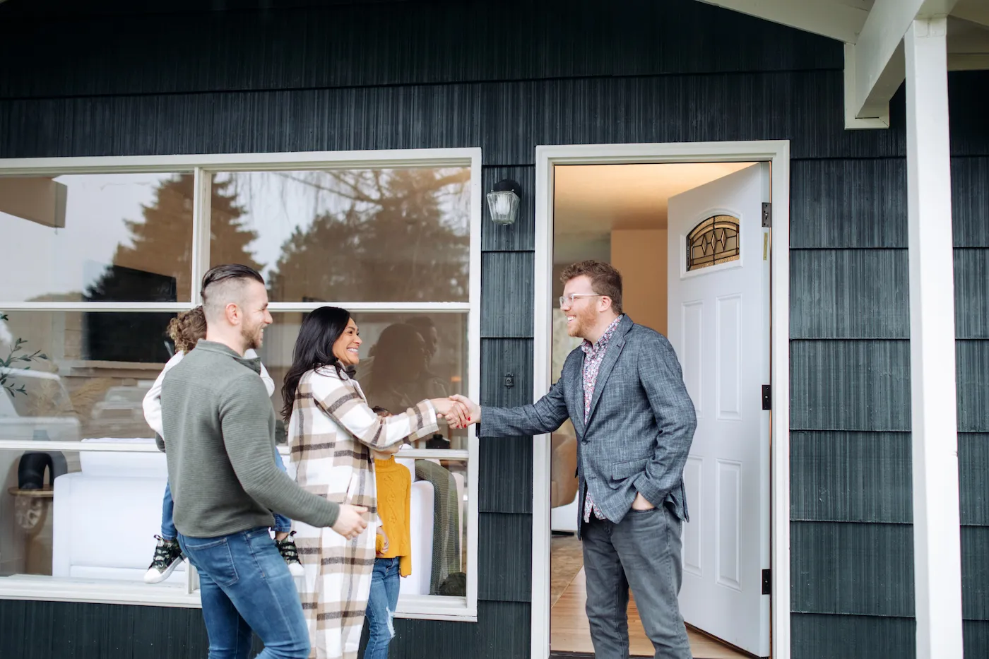 Family meeting with a mortgage professional outside their home.