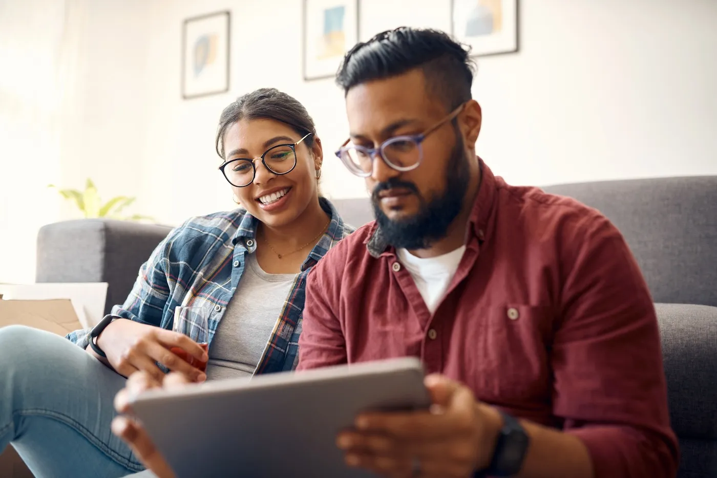 Shot of a young couple using a digital tablet while relaxing on the couch at home.