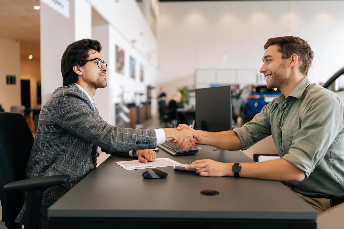 Side view of happy smiling client male purchasing automobile in dealership.