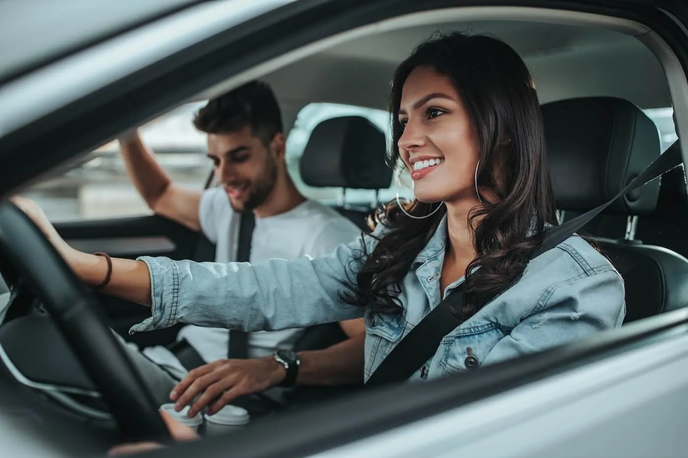 Smiling woman driving a car with a male passenger