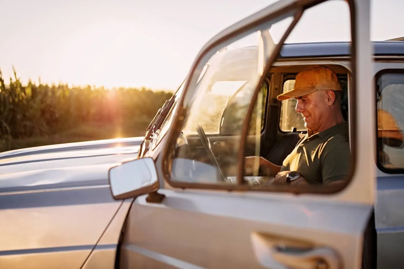 Senior man in a cap is using laptop in his car