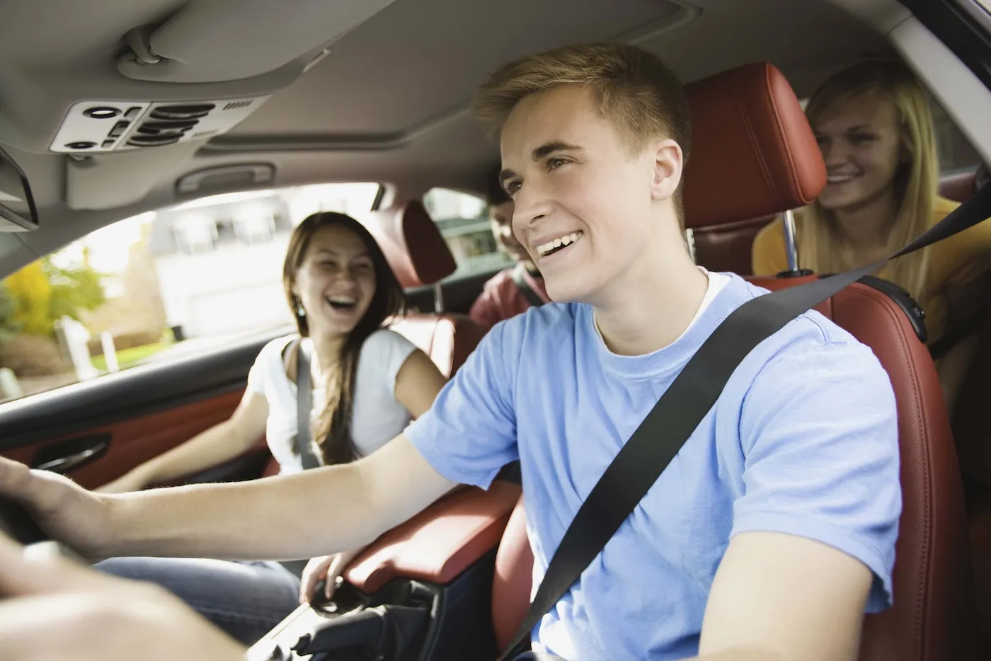 Smiling college students in a car together.