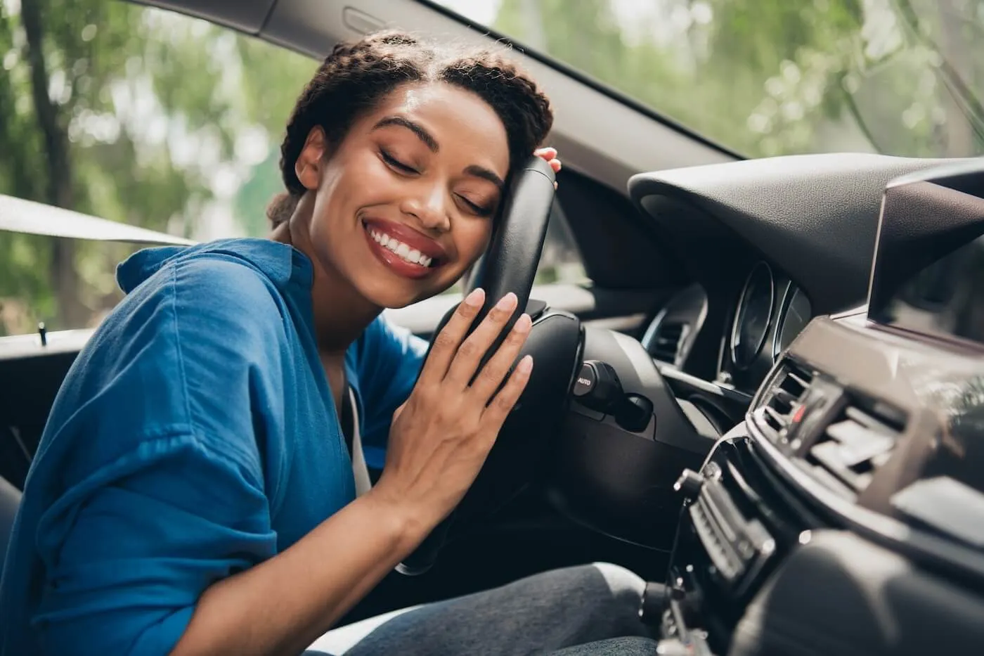 Smiling young woman leaning towards the steering wheel