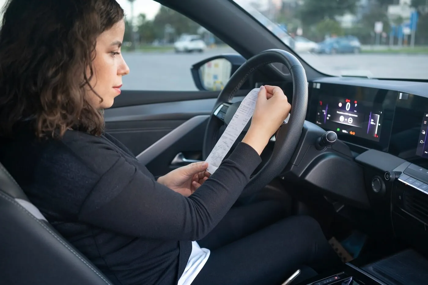 Concerned woman in the car holding a violation notice