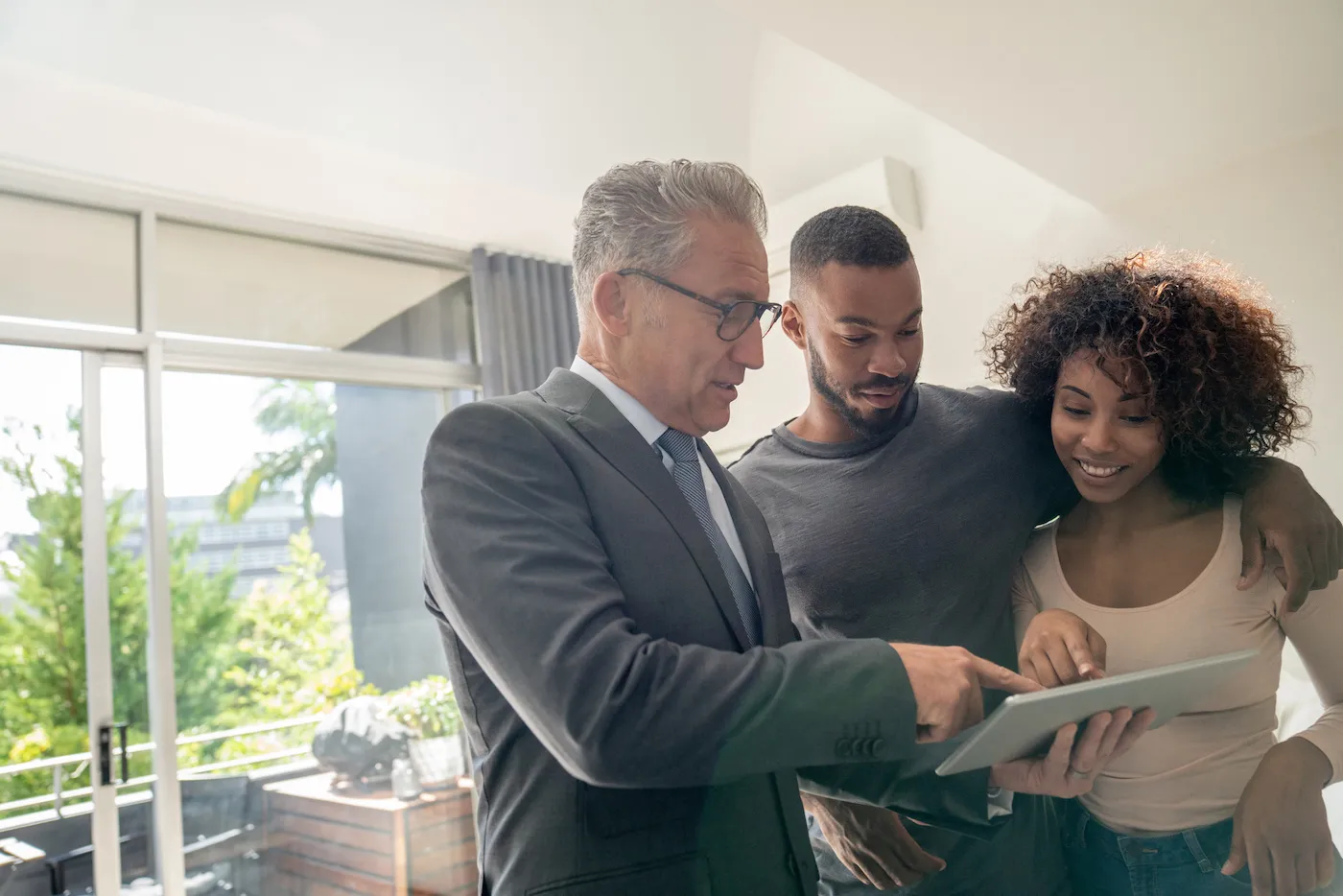 Landlord and couple standing in apartment looking at Experian RentBureau on a tablet