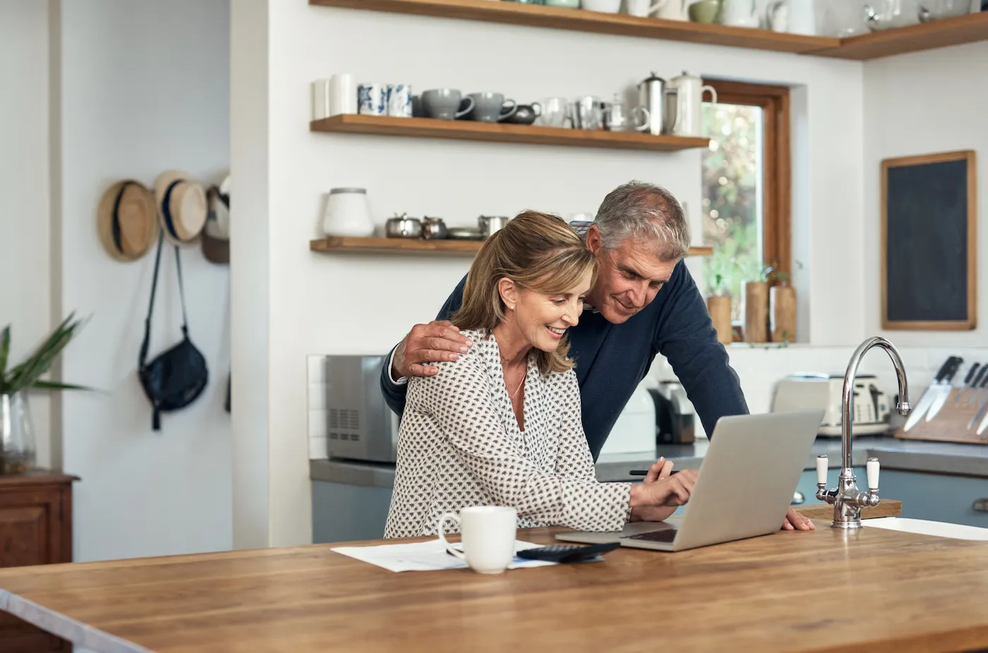 A senior couple planning their finance and paying bills while using a laptop in their kitchen.