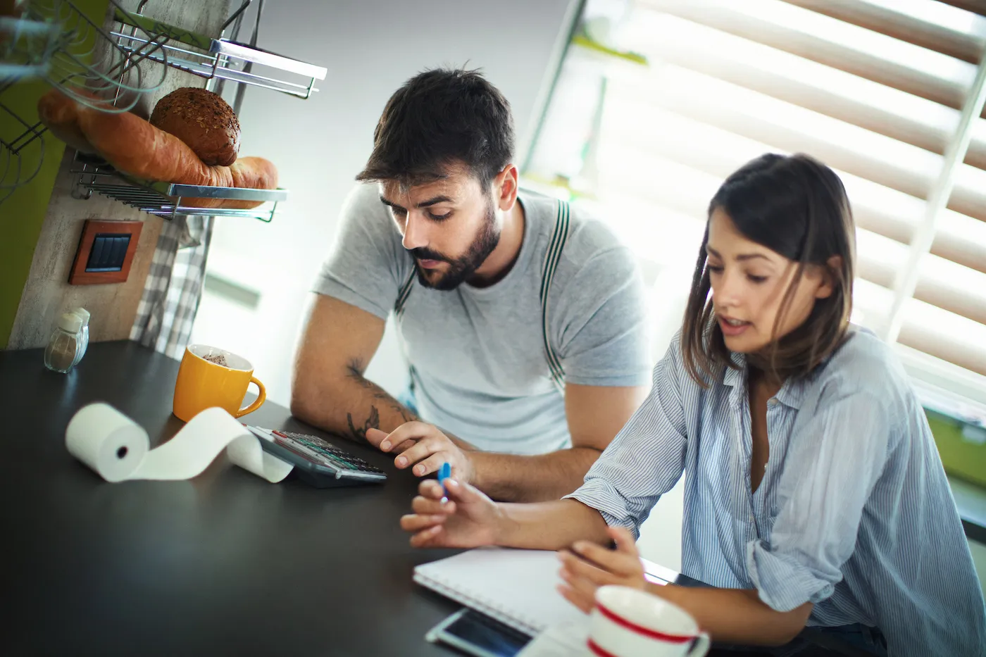 Closeup front view of a mid 20's couple doing their monthly expenses on a tight budget and considering debt consolidation