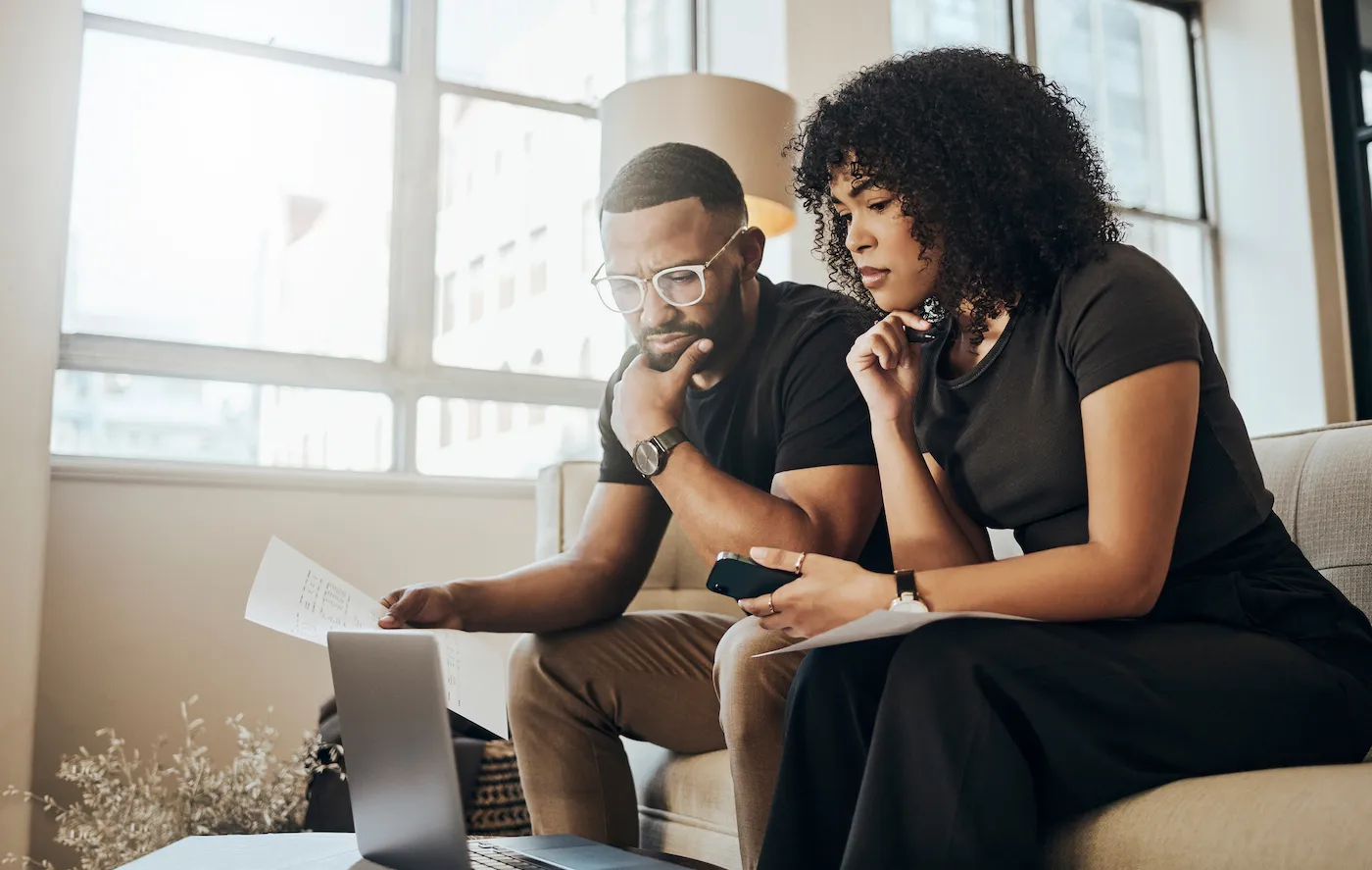 Uncertain-looking couple considering taking out a personal loan, looking at their finances