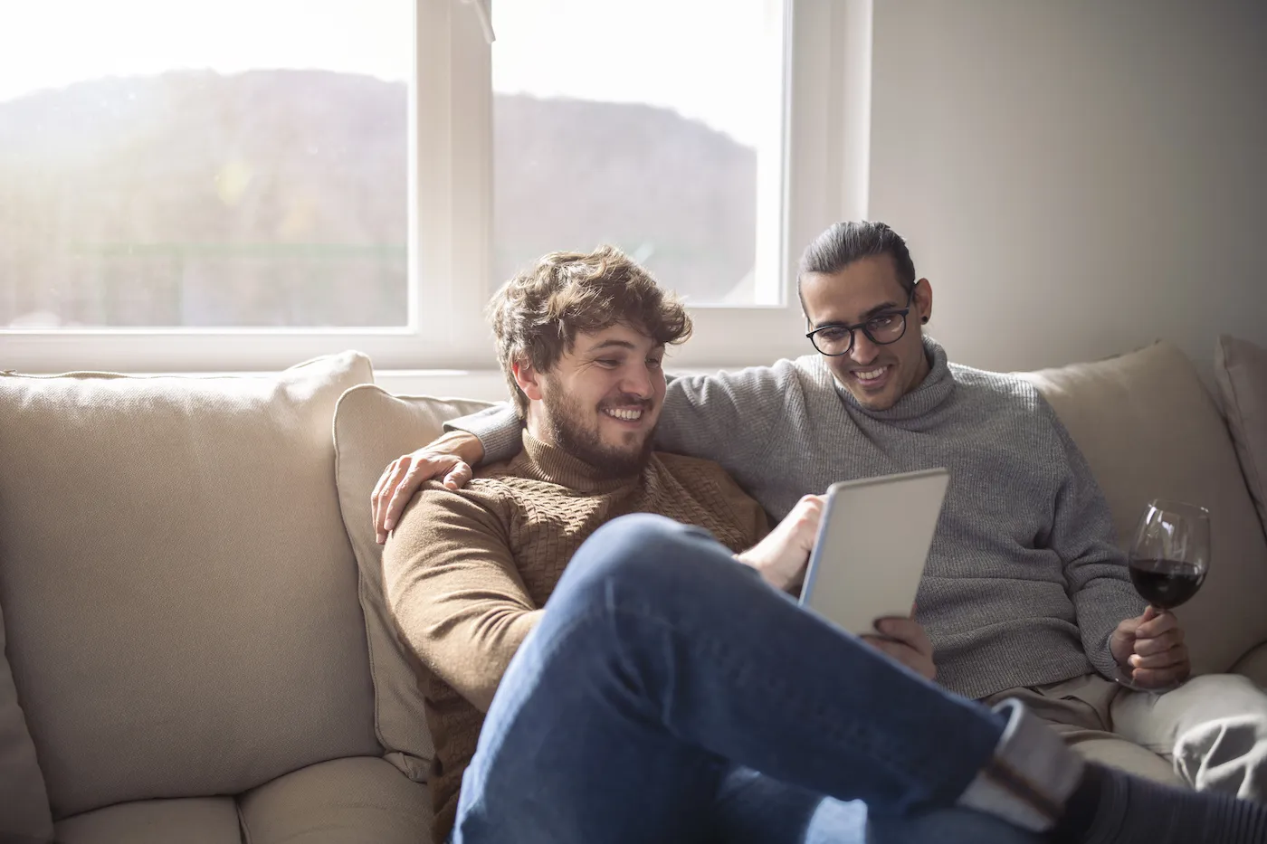 Two men using digital tablet together at home.