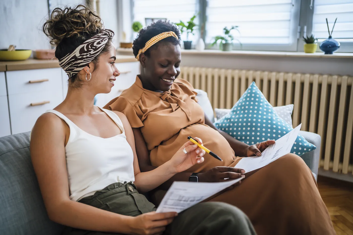 Young couple sitting on the couch reviewing paperwork to plan their financial goals