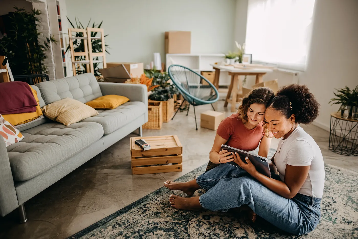 Couple looking at design photos on a tablet while sitting on the floor of their new apartment.