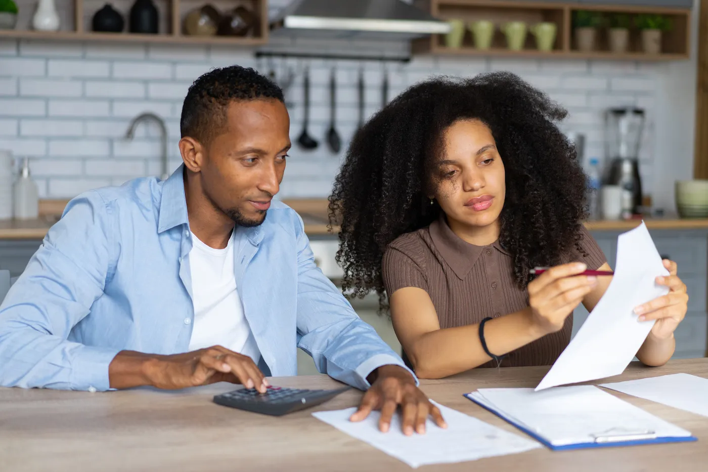 A couple reading paperwork together to understand why their mortgage APR is higher than the interest rate.