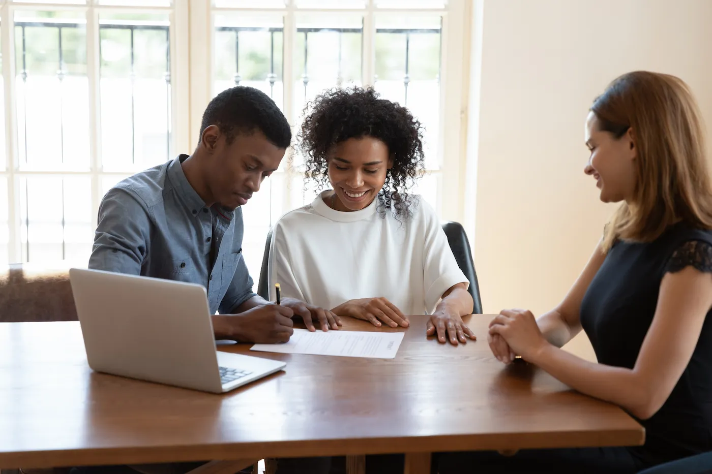 Couple signing mortgage papers with realtor