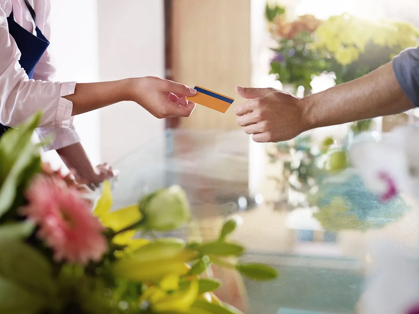 Two hands exchanging a credit card between them.