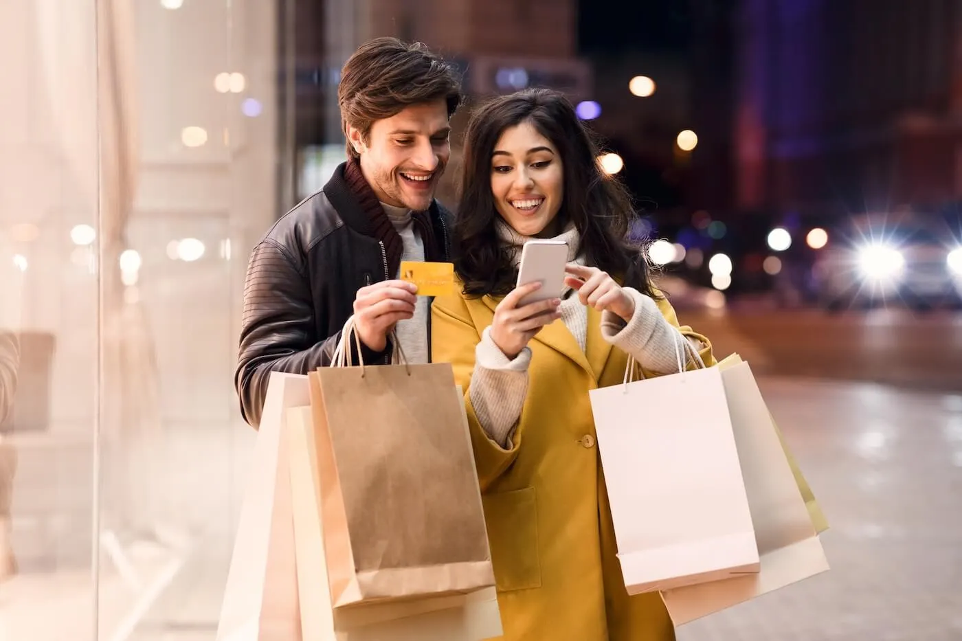 Happy couple checking their credit card rewards in the smartphone after shopping