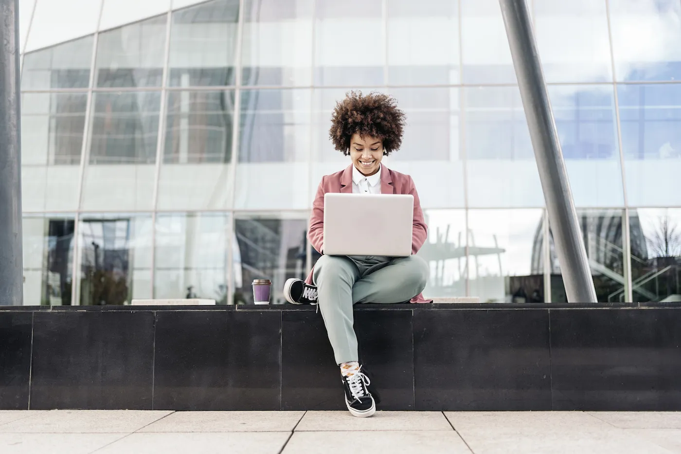 A woman wearing wireless headphones and using a laptop outside to dispute credit report errors