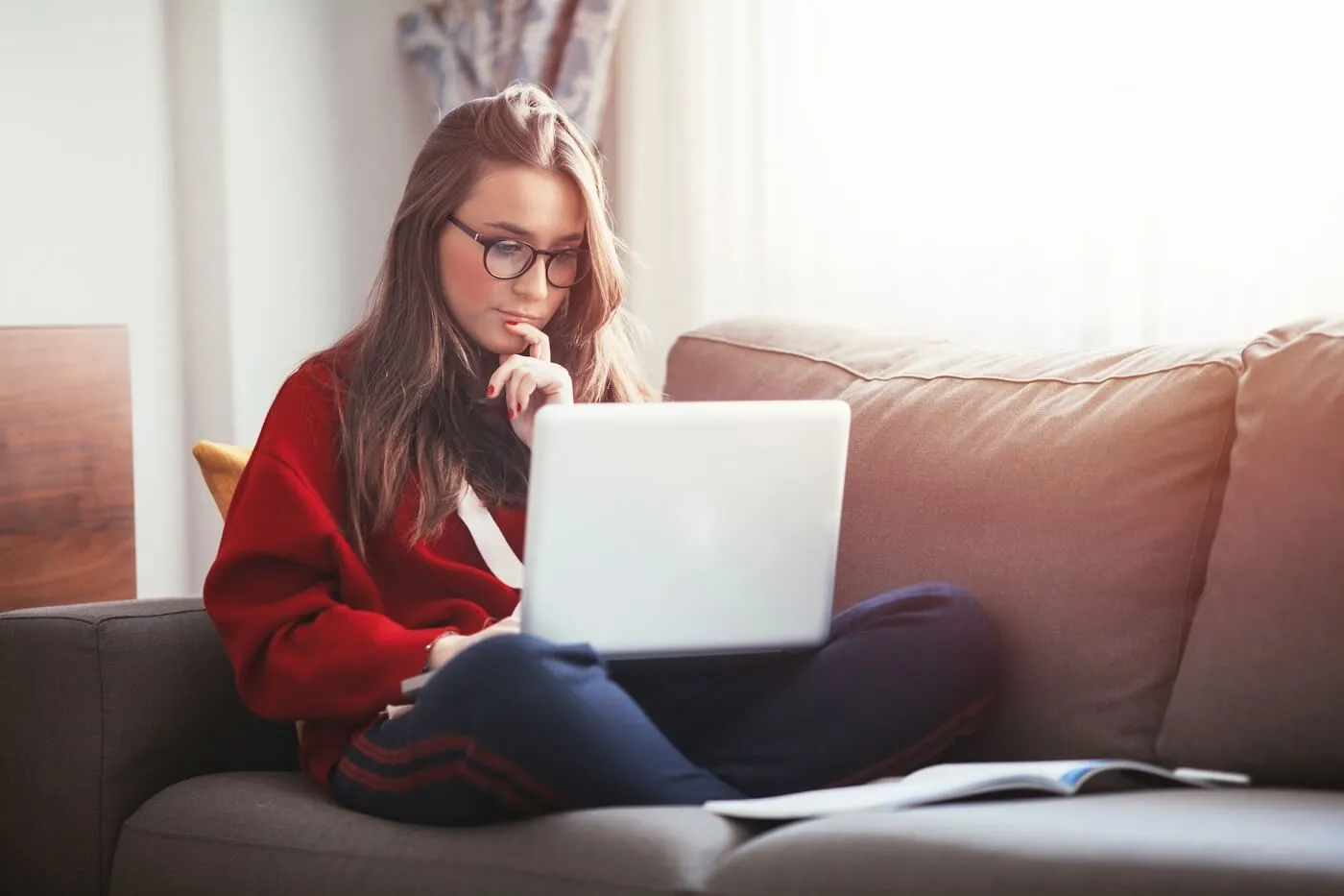 Young woman using her laptop while sitting on the sofa in the living room