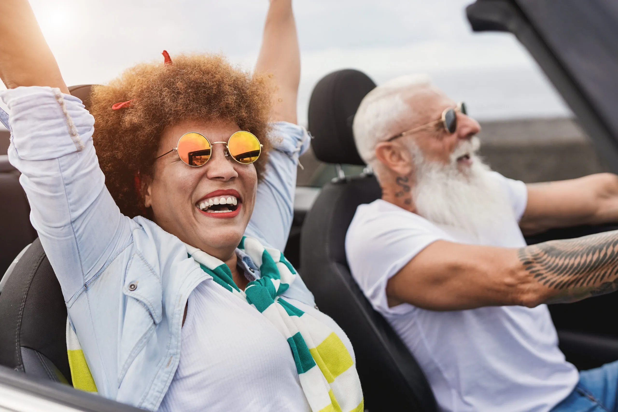 Happy senior couple enjoys driving convertible car on a road trip