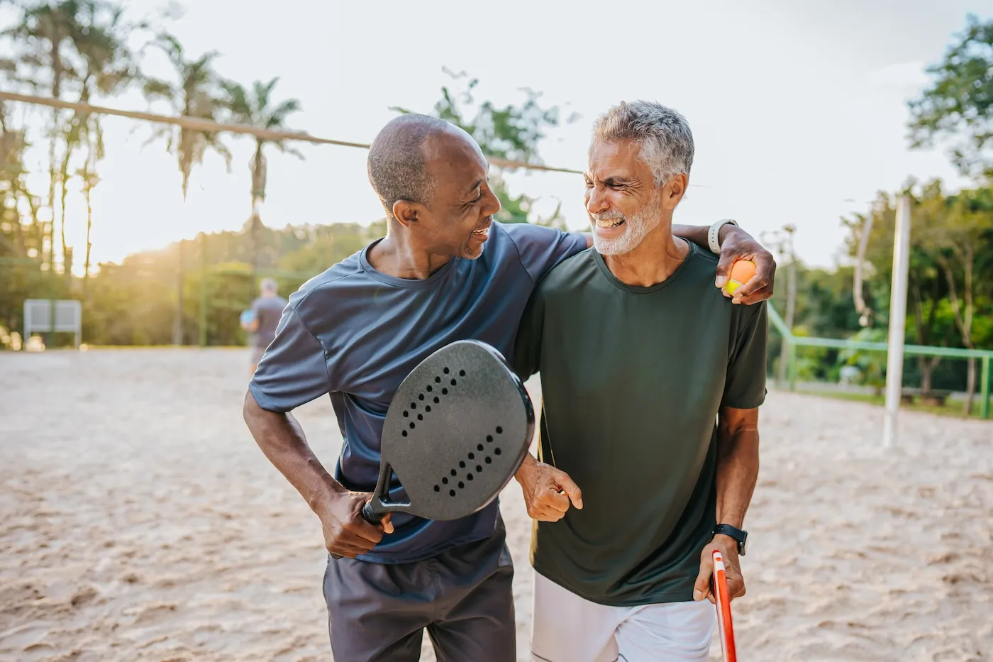 Two senior friends playing tennis on sand tennis court