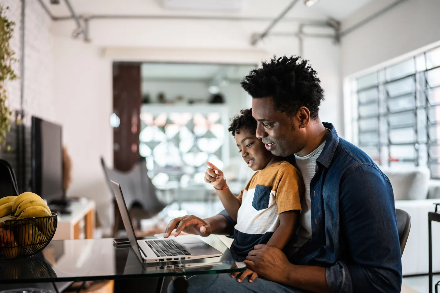 Father using his laptop with son to plan college savings.