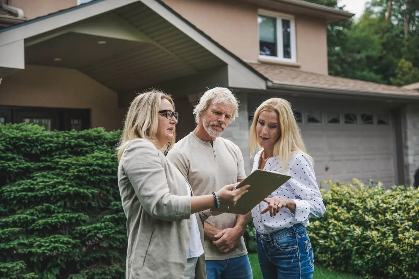 Mature couple discussing the house inspection report with a female agent on a front yard