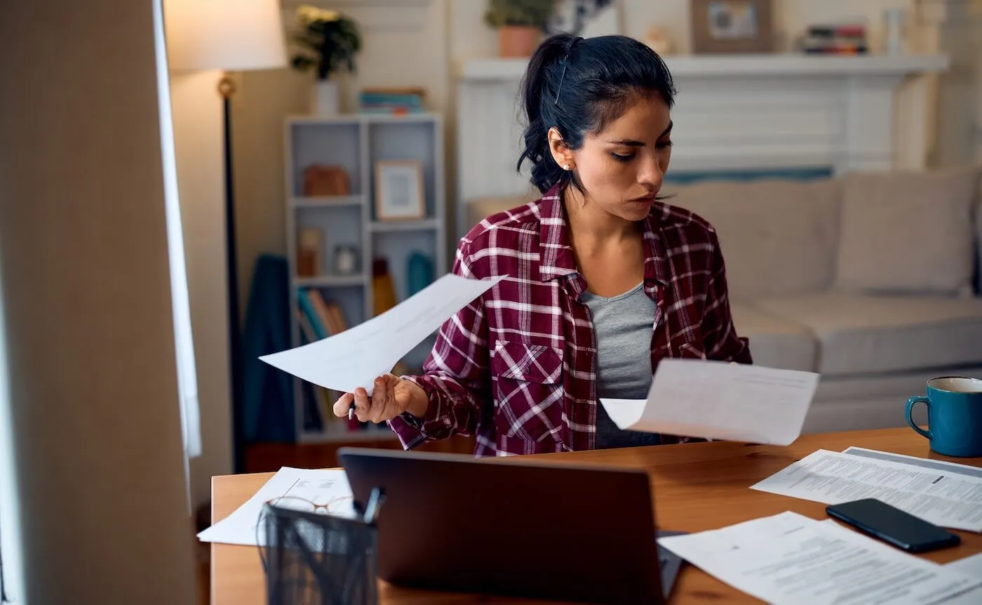 Concerned woman reviewing the bills while using the laptop at home