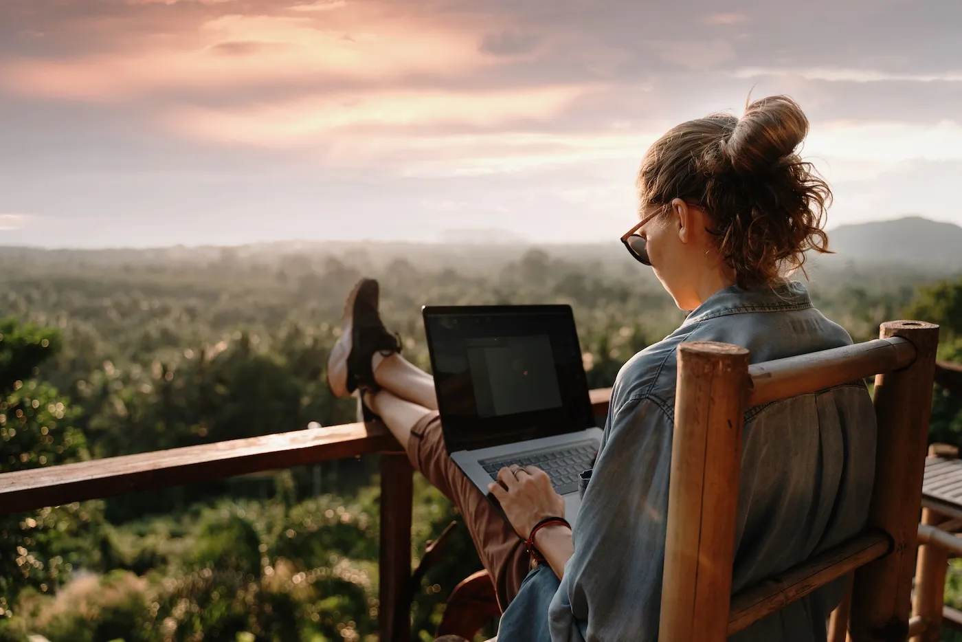 Young business woman working at the computer in cafe on the balcony on a mountain.