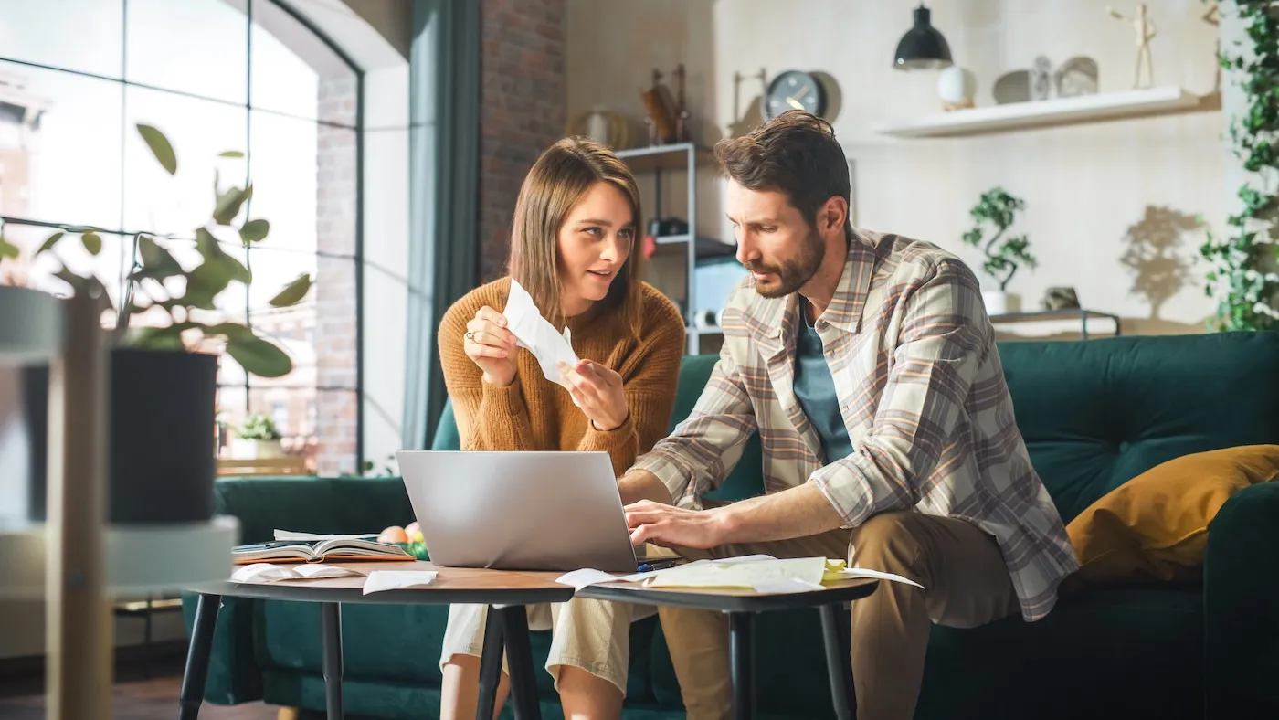 Couple using laptop and reviewing the bills in the living room