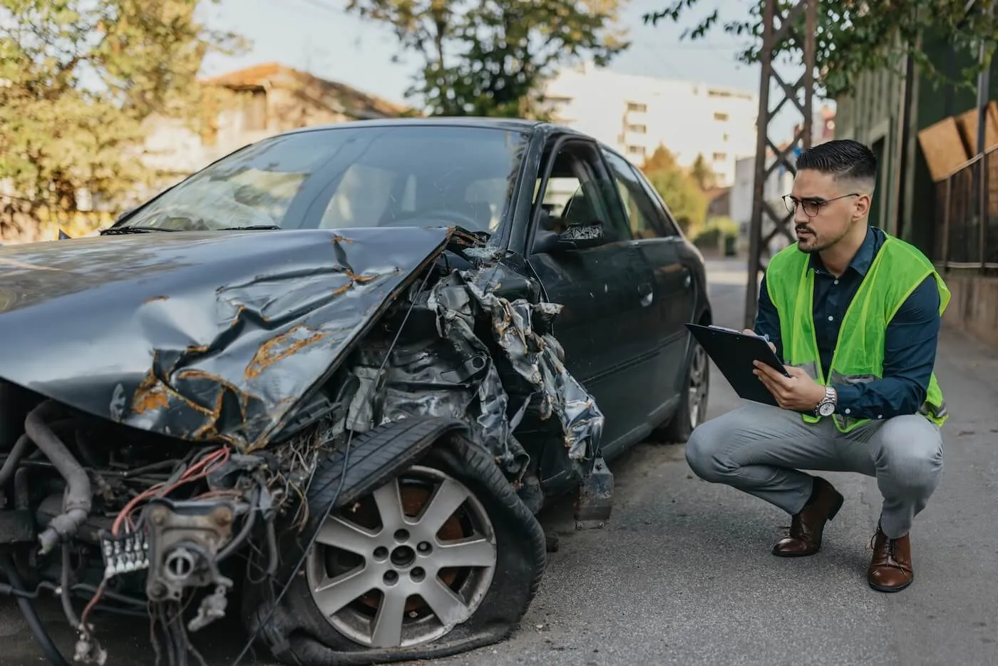 Male agent with a tablet inspecting a totaled car