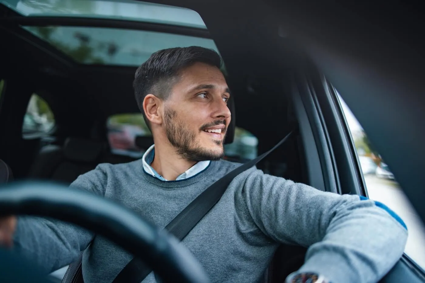 Smiling man looking away while driving a car