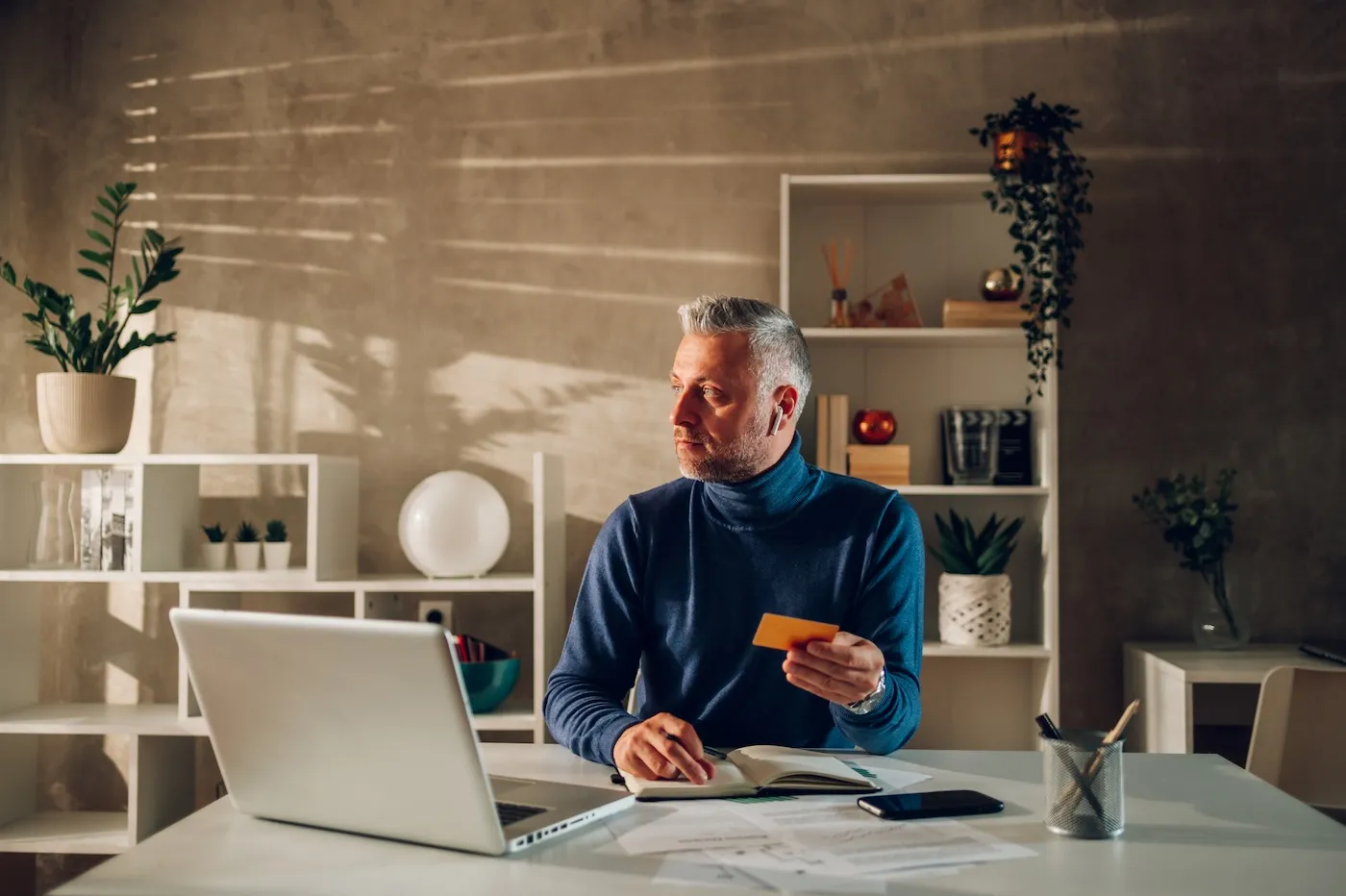 A man holding credit card and using laptop at home.